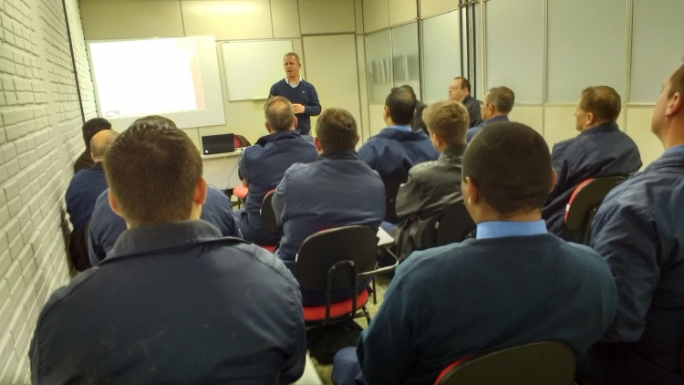 Imagem com colaboradores da empresa reunidos em uma sala de treinamentos.