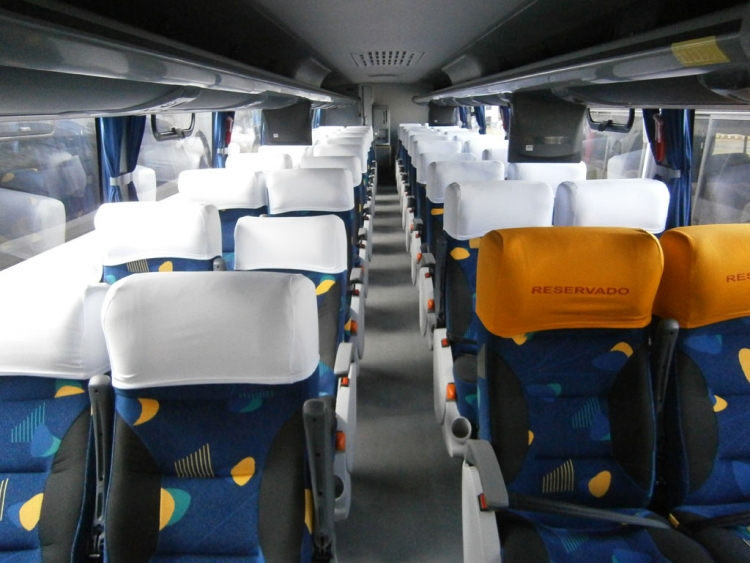 Imagem interna de um ônibus Mascarello R8. Poltronas soft, com 3 estágios para reclinamento proporcionando muito conforto para o passageiro. Porta copos individuais e amplo espaço entre as poltronas.
